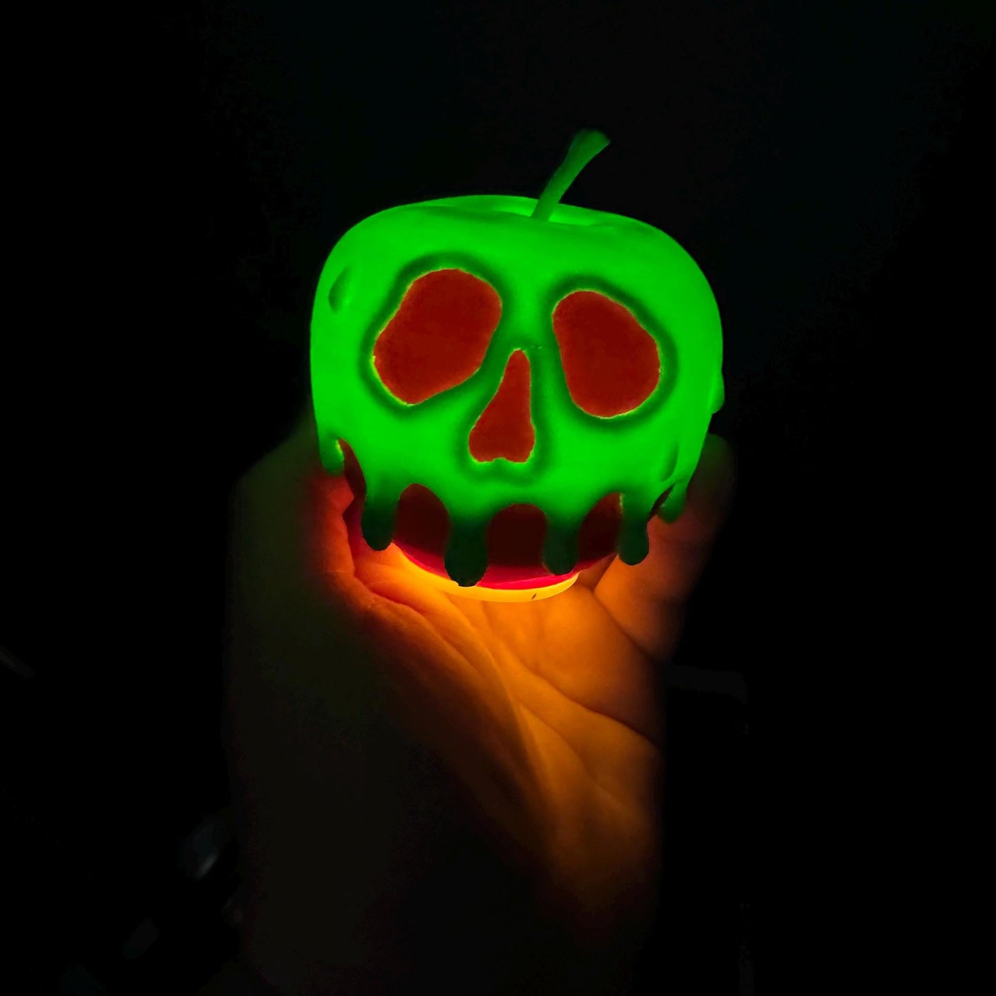 A close up of a light up poison candy apple featuring a realistic skull like dripping design with a vibrant glow.
