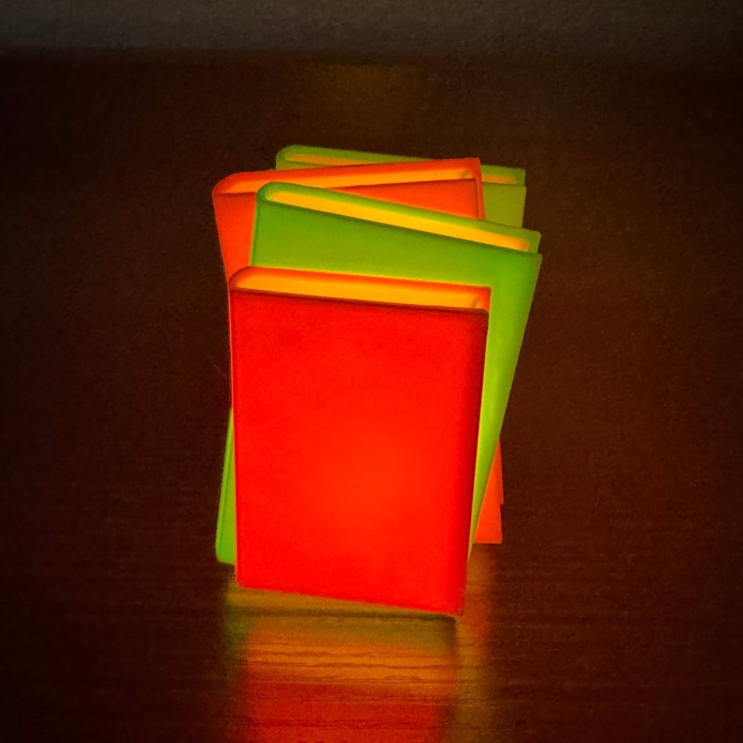 Neon pink and green light up stack of books standing up on a bookshelf.