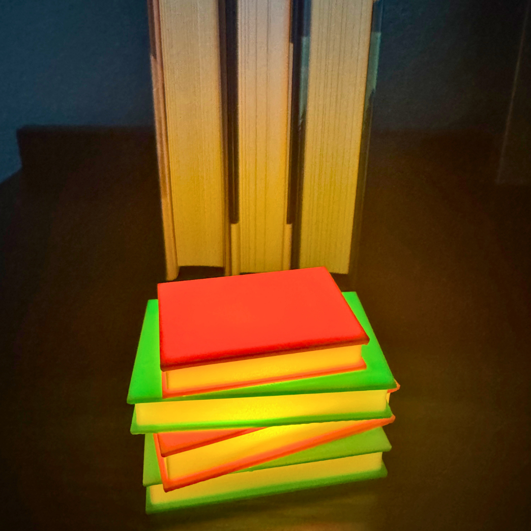 Neon green and pink light up stack of books sitting on a bookshelf with books stacked behind them.