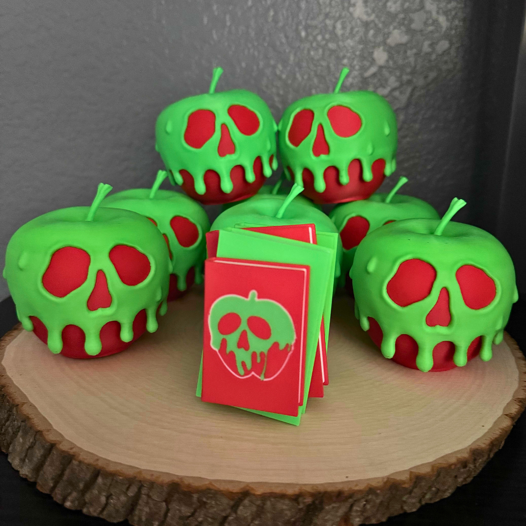 Poison apple light up stack of books with the light turned off standing on a piece of wood surrounded by evil queen poison apples.