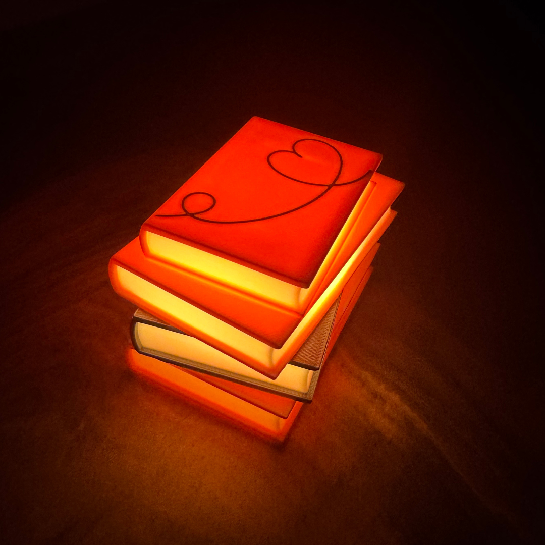 Stack of pink and silver books decoration lit up sitting on a bookshelf.
