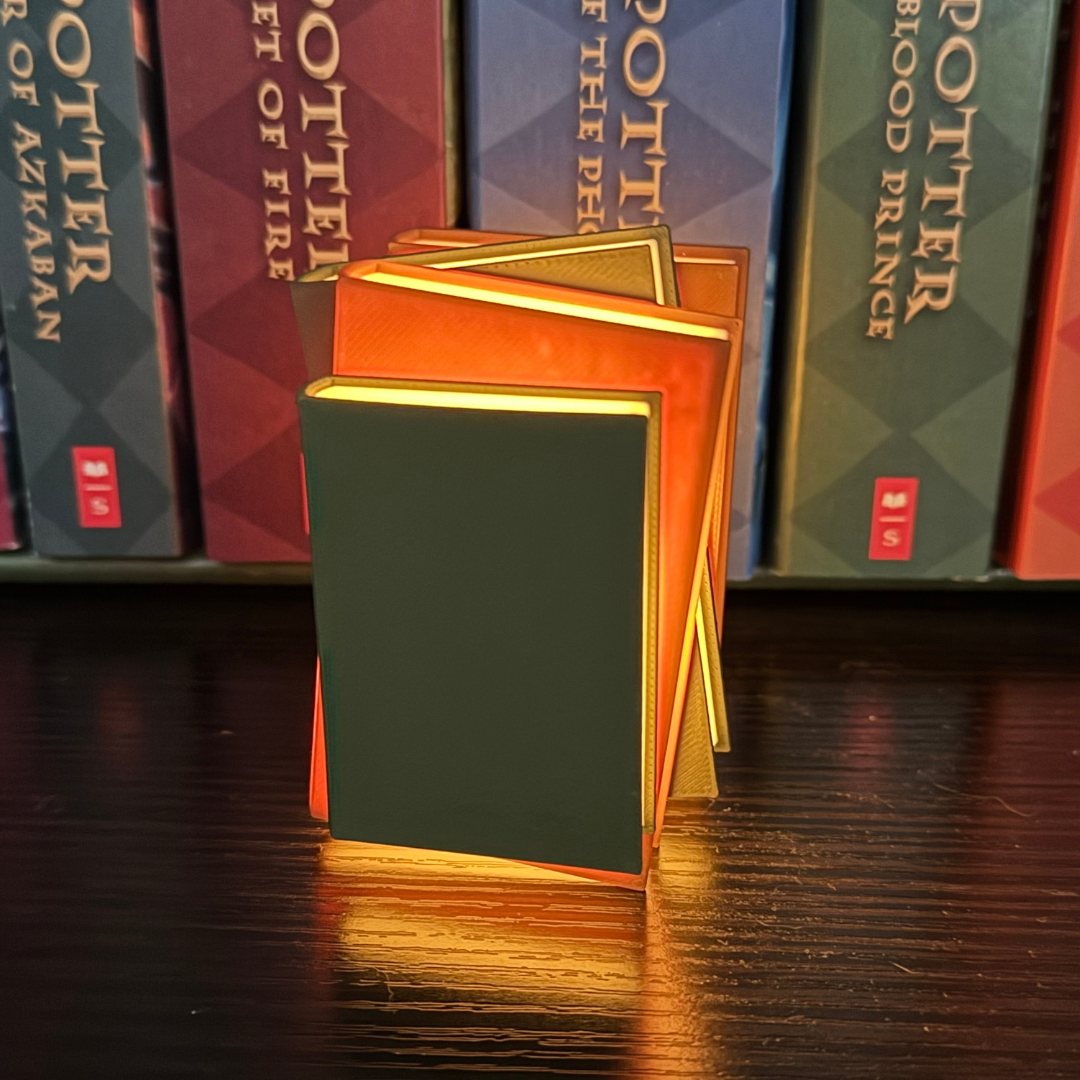 View of the cozy brown and green light up book stack standing up showing off the front view while being in front of a set of Harry Potter books.