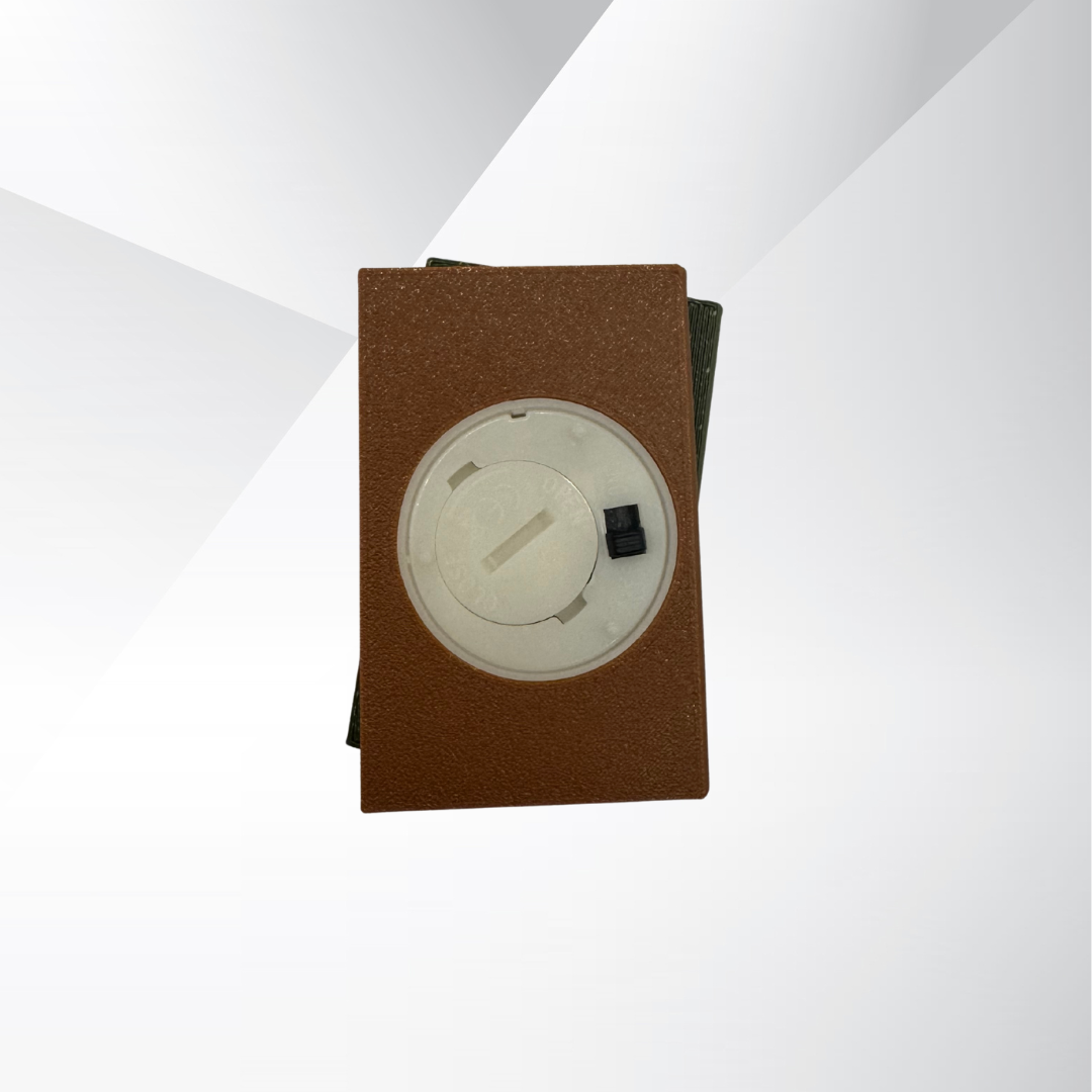 The bottom view of the cozy brown and green light up book stack showing the on and off switch and where the batteries can be replaced on a white and silver background.