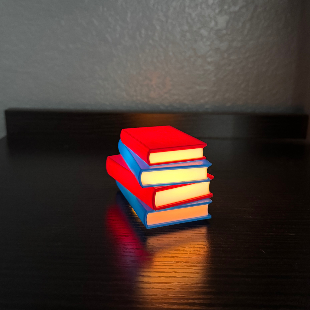 Vibrant red and blue light up stack of books sitting on a wooden shelf as book nook decor.
