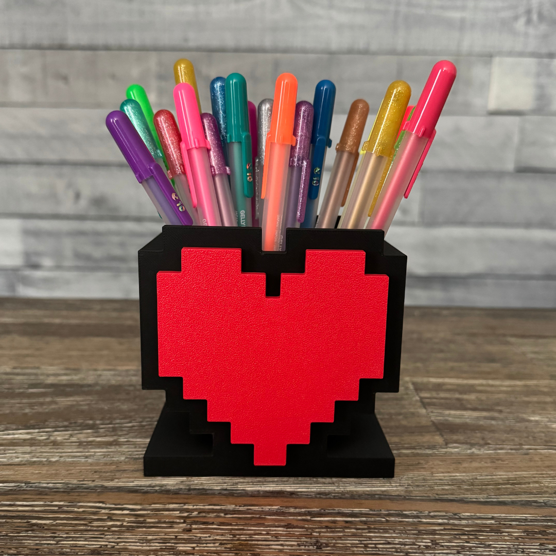 8-Bit Pixel Heart Gaming Pen & Pencil Holder with pens inside while sitting on a wooden table.