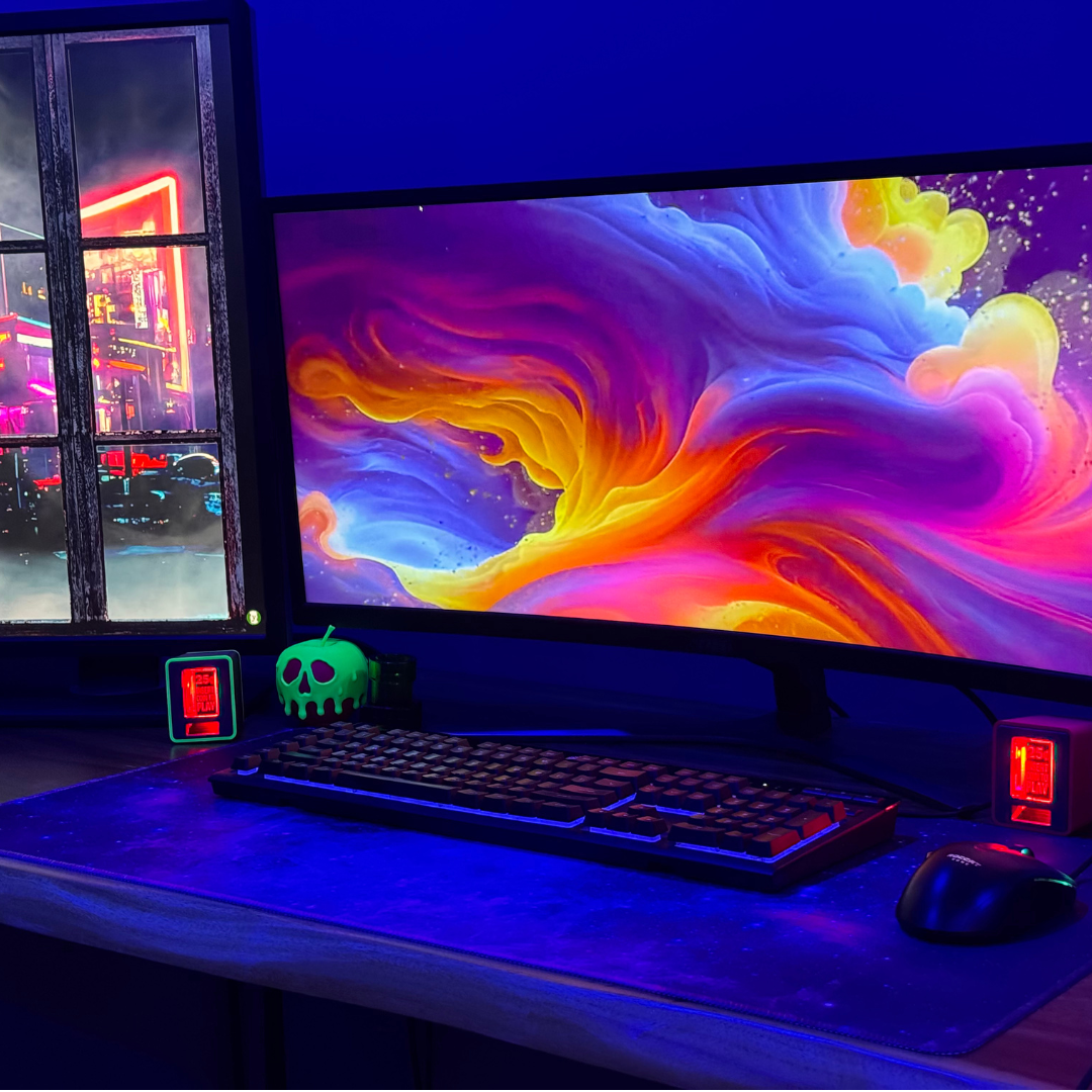 A full gaming desk setup featuring dual monitors and two TinyBrights™ Insert Coin Cubes glowing red on each side, creating a retro arcade ambiance.