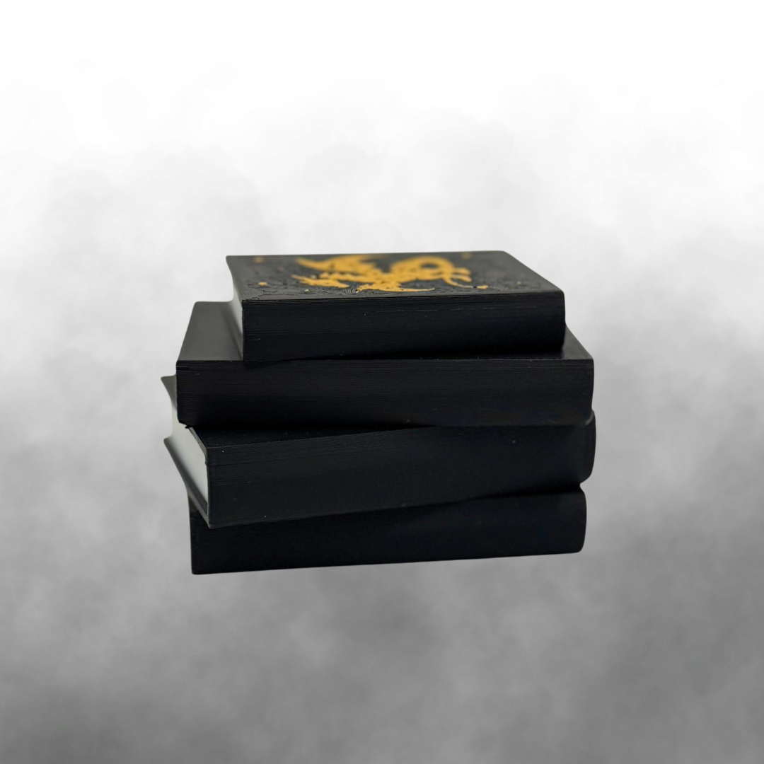 The binding view of a fantasy dragon light up stack of books with the light turned off on a smokey grey background.