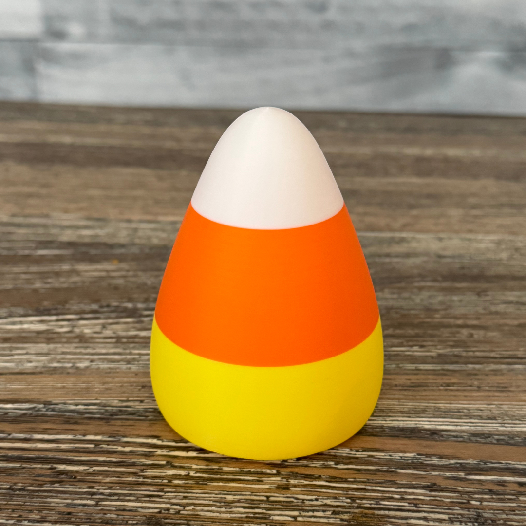 A candy corn shaped light sitting on a wooden dining room table as fall decor.