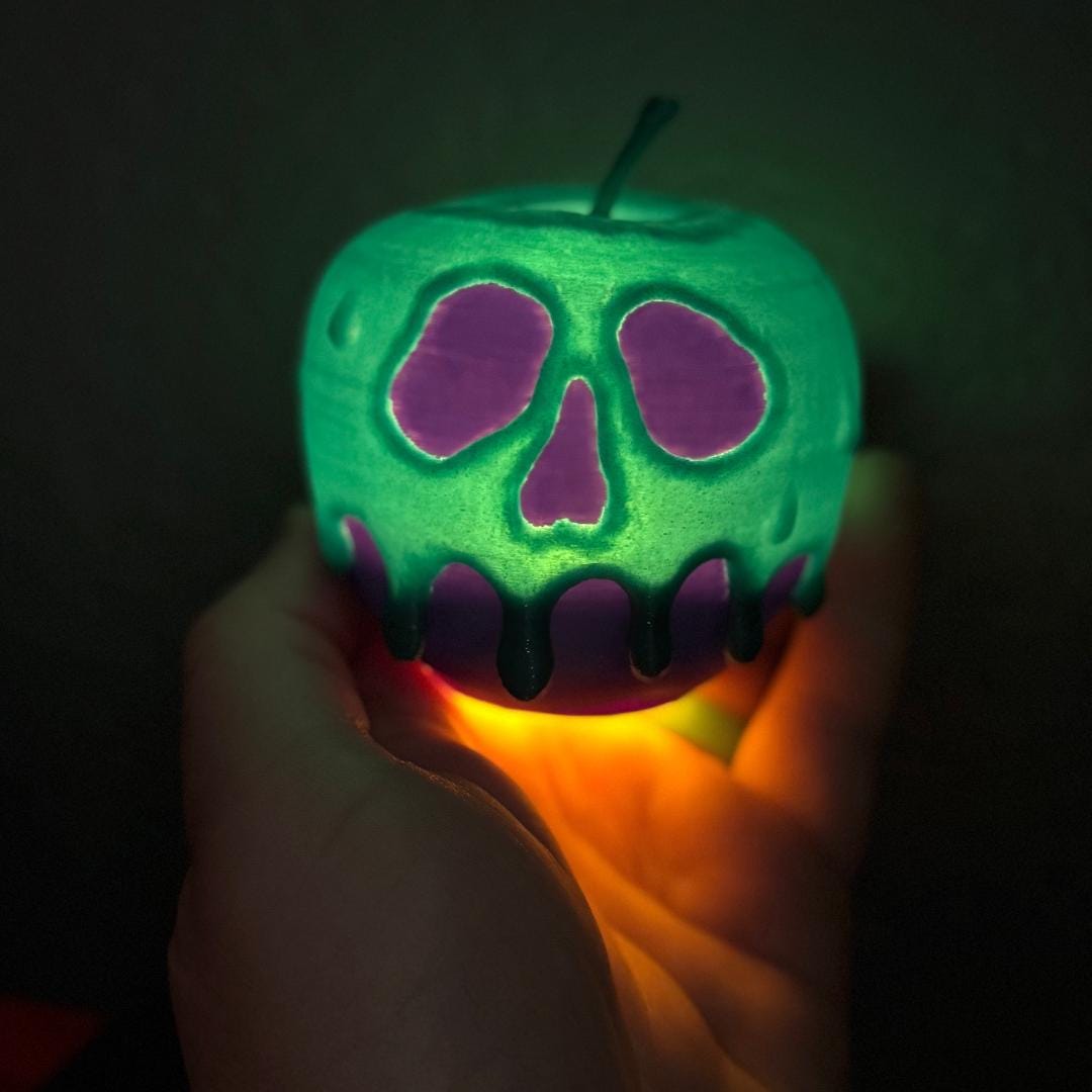 A close up of a purple and teal light up poison candy apple featuring a realistic skull like dripping design with a vibrant glow.