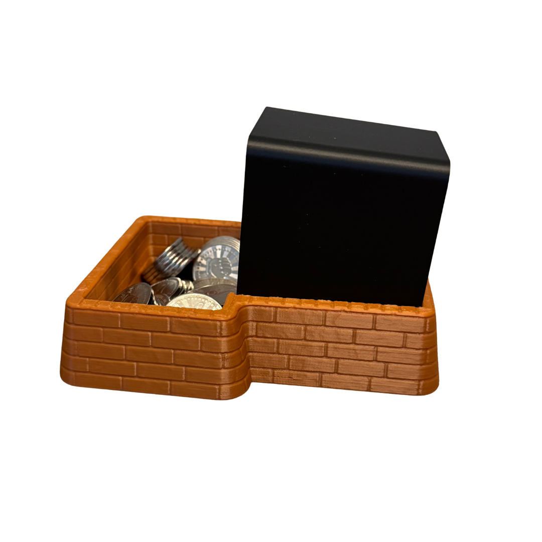 Left side of the brown brick coin tray with a black Insert Coin Cube inside.