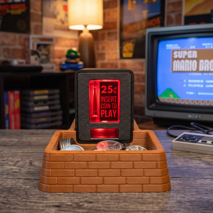 A brown brick coin tray with an Insert Coin Cube sitting on top filled with arcade tokens sitting on a wooden table with a retro CRT TV in the background.