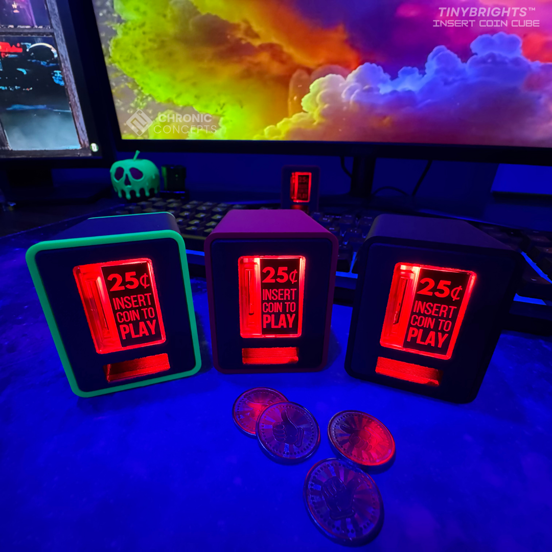 Three TinyBrights™ Insert Coin Cubes glowing beside a gaming keyboard and coins, set in a purple and blue RGB-lit workstation.