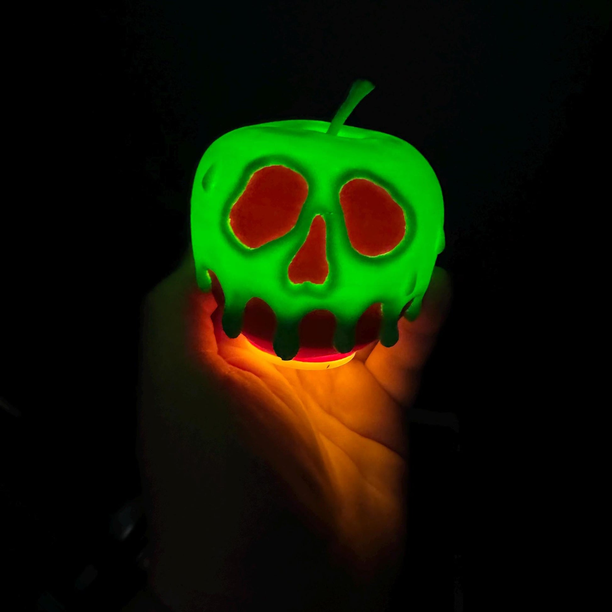 A close up of a light up poison candy apple featuring a realistic skull like dripping design with a vibrant glow.