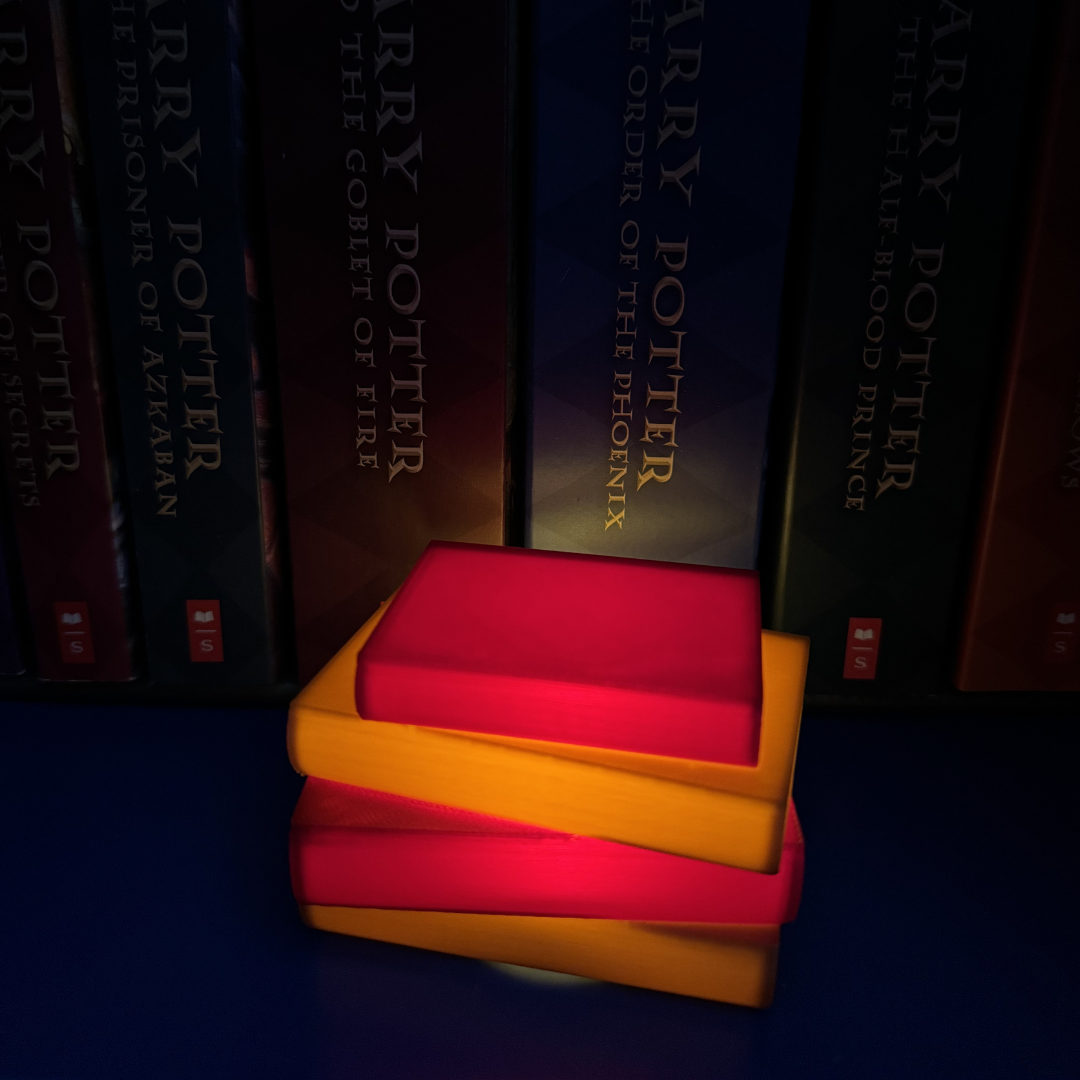 Maroon and brown book light lit up sitting next to Harry Potter books.