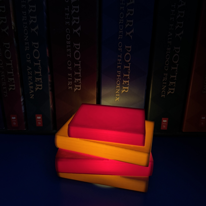 Maroon and brown book light lit up sitting next to Harry Potter books.