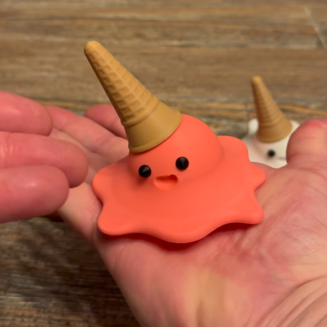 View of strawberry 3d printed melting ice cream cone made by Chronic Concepts being held in the palm of a hand to depict the size of the sculpture.