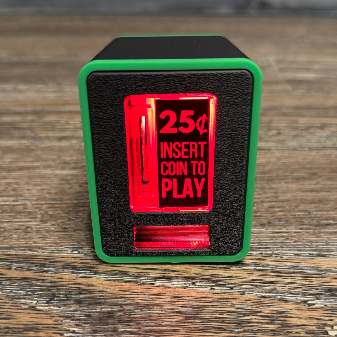 Studio close-up of the neon green TinyBrights™ Insert Coin Cube showing the arcade-style coin slot and front panel on wooden table.