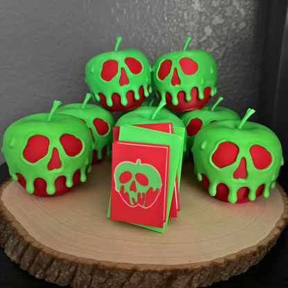 Poison apple light up stack of books with the light turned off standing on a piece of wood surrounded by evil queen poison apples.