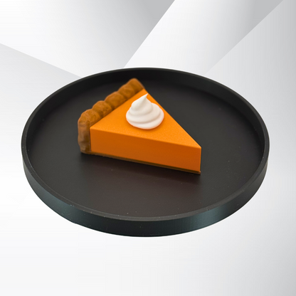 A pumpkin pie light with the light turned off sitting on a black tray with a white and silver background.