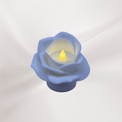 A white 3d printed rose tea light holder with a tea light turned on, on an off white background.