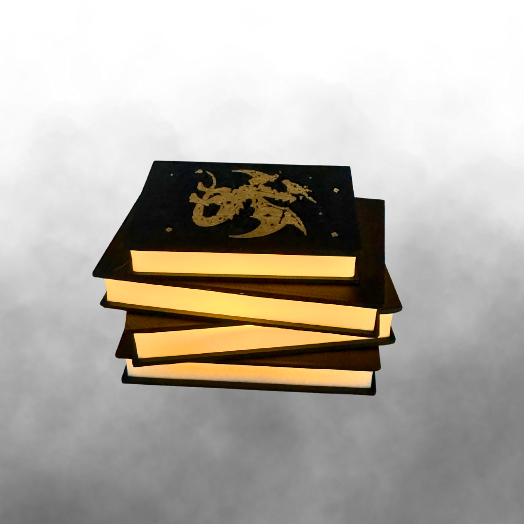 The side view of the fantasy dragon light up stack of books with the light on with a smokey grey background.
