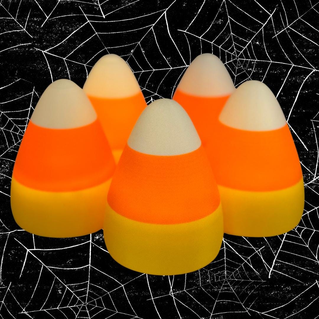Five glowing candy corn shaped lights, casting a warm orange, yellow, and white glow with a black and white spider web background.