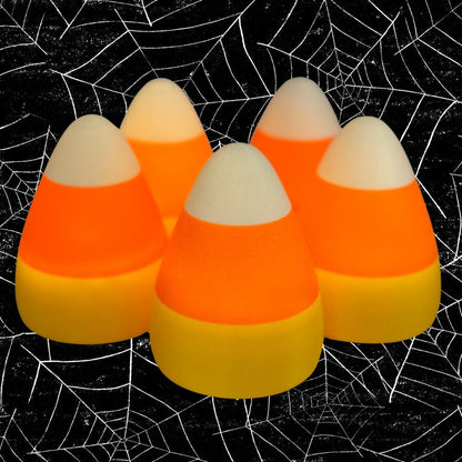Five glowing candy corn shaped lights, casting a warm orange, yellow, and white glow with a black and white spider web background.