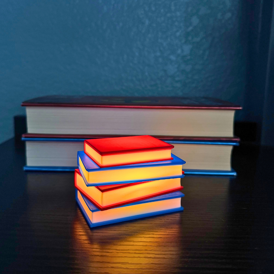 Vibrant red and blue light up stack of books sitting on a bookshelf with Hunger Games books stacked behind them.