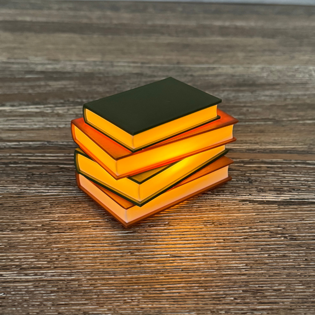 Cozy brown and green light up book stack lit up sitting on a wooden shelf.